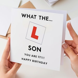 May include: A white birthday card with the text "WHAT THE... SON YOU ARE 17!!! HAPPY BIRTHDAY". The card features a red "L" in a gray square, a symbol for learner drivers.