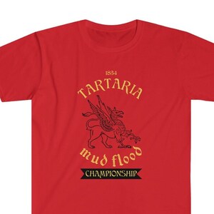 K&ouml;nnte beinhalten: Rotes T-Shirt mit einer goldenen Grafik einer gefl&uuml;gelten Kreatur mit dem Text "1834 Tartaria mud flood championship"