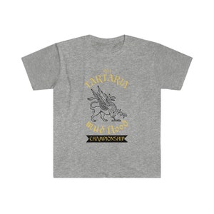 K&ouml;nnte beinhalten: Ein graues T-Shirt mit einer Schwarzwei&szlig;illustration einer mythischen Kreatur mit Fl&uuml;geln. Der Text "1854 Tartaria mud flood championship" ist in Gold auf dem Shirt gedruckt.