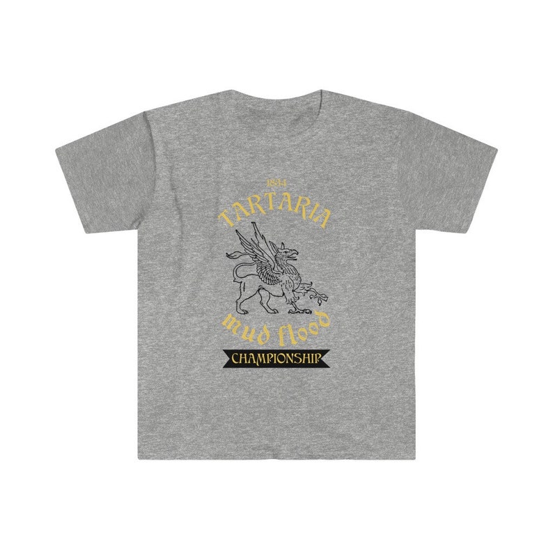 K&ouml;nnte beinhalten: Ein graues T-Shirt mit einer Schwarzwei&szlig;illustration einer mythischen Kreatur mit Fl&uuml;geln. Der Text "1854 Tartaria mud flood championship" ist in Gold auf dem Shirt gedruckt.
