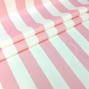 Könnte beinhalten: Rosa-weiß gestreiftes Stoff mit glatter Textur. Der Stoff ist in der Hälfte gefaltet, wobei die Streifen vertikal verlaufen.