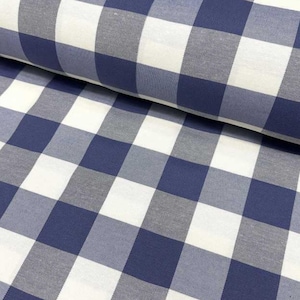 Op de afbeelding: Close-up van een stof met een klassiek blauw, wit en grijs ruitpatroon. De stof is gevouwen en toont de textuur en het herhalende vierkante ontwerp. Het materiaal lijkt katoen of een vergelijkbaar geweven textiel te zijn.