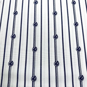 May include: White fabric with a repeating pattern of navy blue ropes with knots. The ropes are arranged in vertical lines.