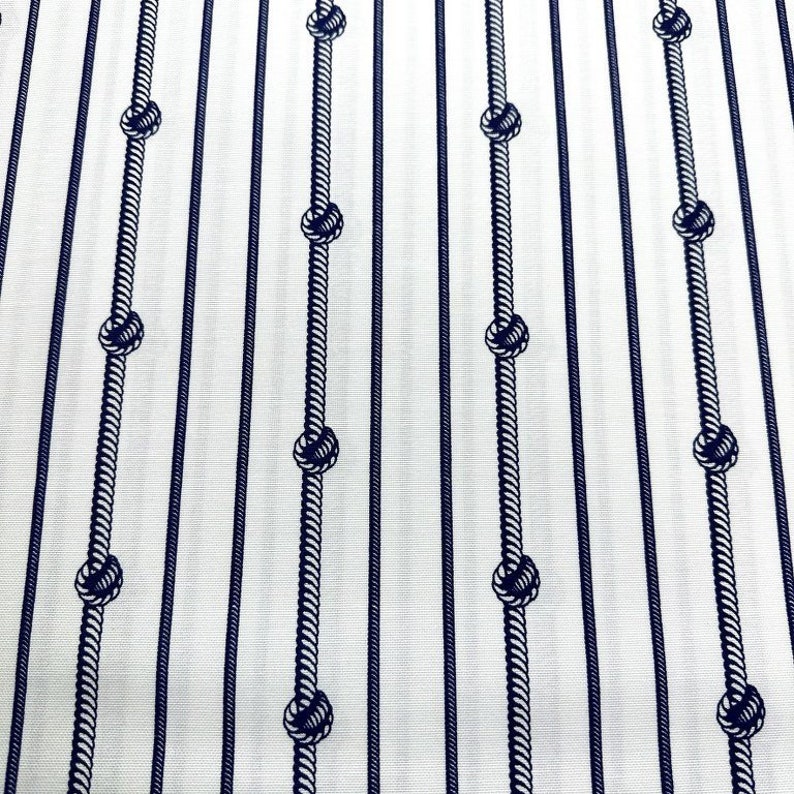 May include: White fabric with a repeating pattern of navy blue ropes with knots. The ropes are arranged in vertical lines.