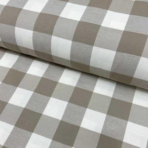 May include: A white and brown gingham fabric with a checkered pattern. The fabric is folded in half, showing the pattern on both sides.