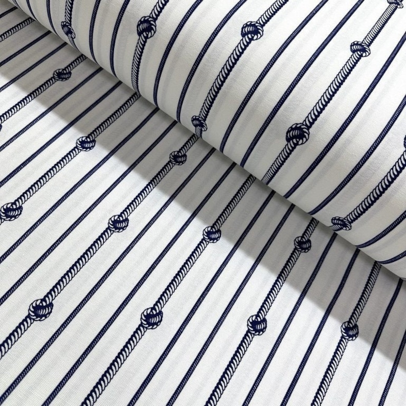May include: White fabric with navy blue stripes and rope knots. The fabric is folded in half, showing the pattern on both sides.