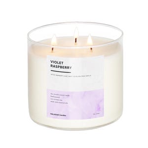 May include: A clear glass jar candle with three wicks. The candle is labeled "Violet Raspberry" with the notes "Raspberry Glaze, Sweet Pea Bloom, Fresh Vanilla". The candle is hand-poured with soy-coconut wax and essential oils. The label also says "Naladak Candles" and "Est. 2023".