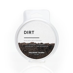 May include: A round, clear container with a black label that reads "DIRT" and "NOTES: EARTHY MUD & FRESH MOSS". The container is filled with a dark brown wax melt and has a white label on the bottom that reads "NALADAK Candles Est. 2023".