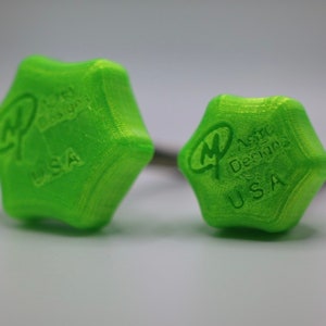 Puede incluir: Dos pomos verdes en forma de estrella con el texto "Astro Design USA" y "Astro Design USA" en ellos.