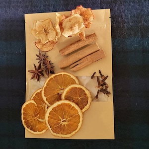 May include: A brown paper bag filled with dried orange slices, cinnamon sticks, star anise, and cloves. These ingredients are commonly used in holiday baking and crafting.
