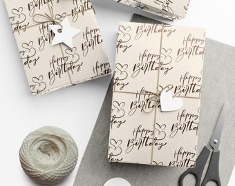 Pode incluir: Três caixas de presente embrulhadas em papel bege com um padrão repetido do texto "Happy Birthday" em escrita preta. As caixas são amarradas com barbante e decoradas com etiquetas de papel branco e corações.
