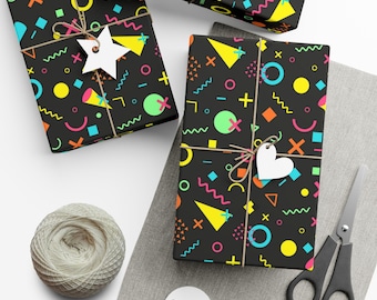 May include: Three gift boxes wrapped in black and white geometric patterned paper with bright yellow, pink, blue, and green accents. The boxes are tied with twine and decorated with white paper stars and hearts.