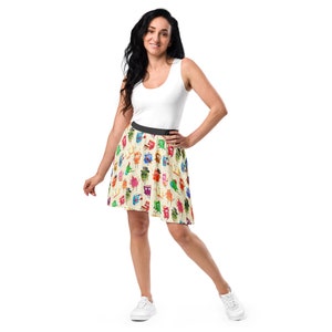 May include: A woman wearing a white tank top and a colorful, whimsical skirt with a pattern of cartoon characters. The skirt is a skater style with a flared silhouette.