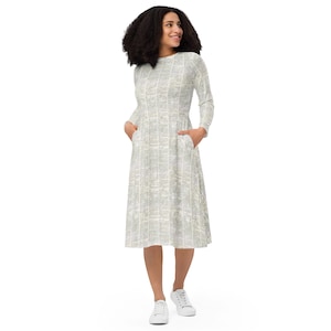 May include: A white dress with a subtle pattern, featuring long sleeves and pockets. The dress has a fitted bodice and a flowing skirt.