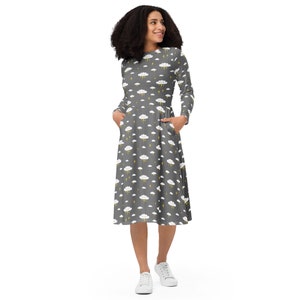 May include: A gray midi dress with a white cloud and yellow lightning bolt pattern. The dress has long sleeves and pockets.