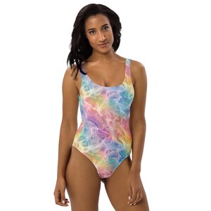May include: A one-piece swimsuit with a colorful, abstract design. The swimsuit features a scoop neckline and a vibrant pattern of swirling pastel colors, including pink, yellow, blue, and purple. The fabric appears smooth and form-fitting.