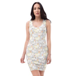 May include: A sleeveless bodycon dress featuring a repeating pattern of white and yellow chickens and white eggs on a light gray background. The dress has a scoop neckline and is made of a stretchy fabric.