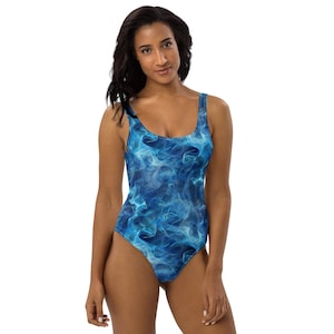 May include: A one-piece swimsuit with a blue and white smoke-like pattern. The swimsuit has a scoop neckline and a low back. The fabric appears to be a smooth, stretchy material. The overall design is a vibrant and eye-catching. The swimsuit is designed for swimming.