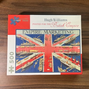 May include: A 500-piece jigsaw puzzle featuring a vintage poster design. The puzzle box displays the text "Hugh Williams Poster for the British Empire" and "Empire Marketing." The artwork depicts ships arranged over a Union Jack flag.