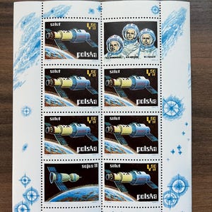 May include: A sheet of Polish postage stamps featuring space exploration themes. The stamps depict spacecraft, cosmonauts, and the text "salut" and "polska". The stamps are in shades of blue, yellow, and white, with a dark blue background.