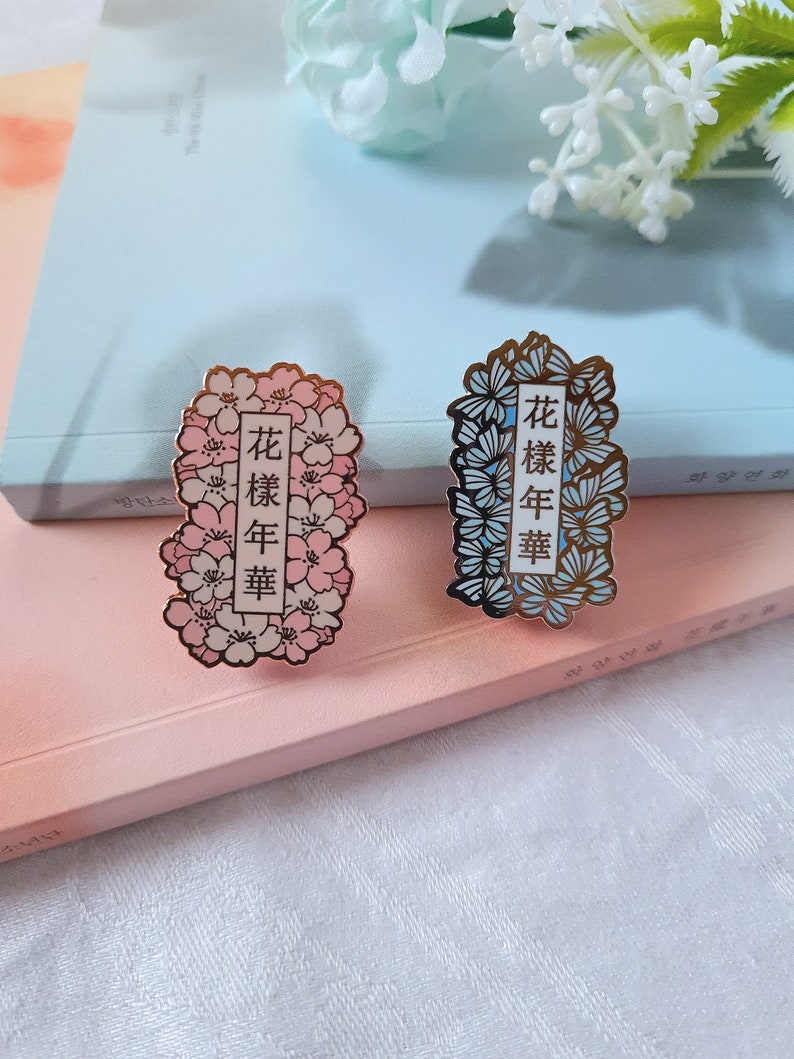 以下が含まれることがあります： 花柄と金色のアクセントが施されたエナメル製のピンが2つ。ピンには中国語で「花樣年華」という文字が書かれており、日本語に訳すと「最も美しい瞬間」という意味です。