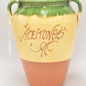 May include: A ceramic olive jar with two handles. The jar is decorated with green, yellow and brown glaze. The jar has the word "Aceitunas" written on it in brown lettering.