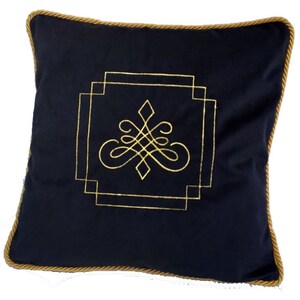 Könnte beinhalten: Ein marineblaues Kissen mit einem goldenen Stickmuster. Das Muster zeigt ein stilisiertes geometrisches Muster mit einer Diamantform in der Mitte.