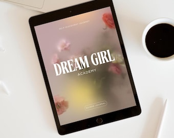 Könnte beinhalten: Ein schwarzes Tablet mit dem Text "DREAM GIRL ACADEMY" und floralen Akzenten. Das Tablet liegt auf einer weißen Oberfläche, neben einem Laptop, einer Kaffeetasse, einem Stift und einer dekorativen Vase.