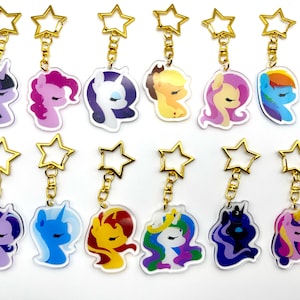 Può includere: Set di 12 portachiavi colorati My Little Pony. Ogni portachiavi presenta un diverso personaggio di pony con un ciondolo a forma di stella dorata e un anello dorato.