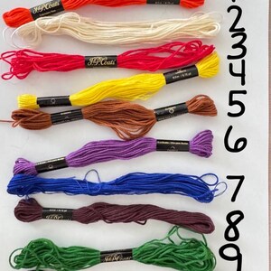 May include: A collection of ten skeins of J&P Coats embroidery floss in various colors, including orange, cream, red, yellow, brown, purple, blue, maroon, green, and black. Each skein is labeled with the brand name and length.