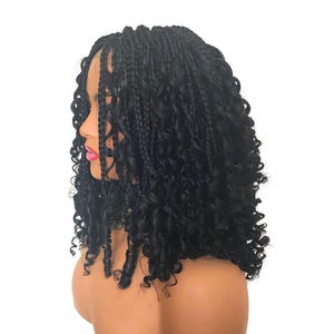 May include: A black braided wig with curly ends. The wig has small, neat braids at the front and top, leading into voluminous, bouncy curls. The hair is styled on a mannequin head, showing the wig's shape and texture against a white backdrop.