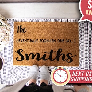 May include: A brown coir doormat with the text "The (EVENTUALLY, SOON-ISH, ONE DAY...) Smiths" in black lettering.