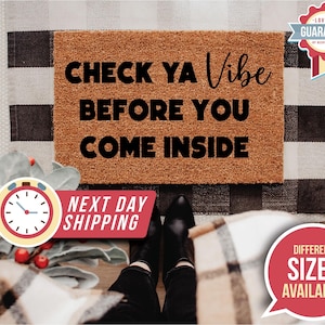 May include: A rectangular doormat with the text "CHECK YA VIBE BEFORE YOU COME INSIDE" in black. The mat is brown and sits on a black and white checkered pattern. A red and white graphic with the words "Different Sizes Available" is in the image.