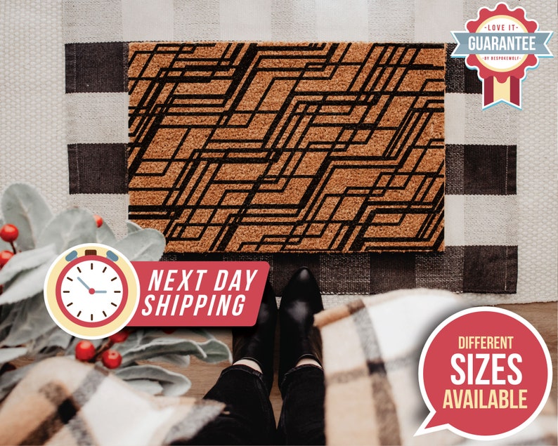 May include: A brown doormat with a black geometric pattern. The doormat is made of coir and has a textured surface. The text "Next Day Shipping" is printed on a red banner below the doormat.