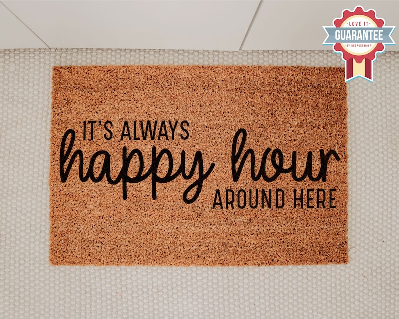 May include: A brown coir doormat with the text "It's always happy hour around here" in black lettering.