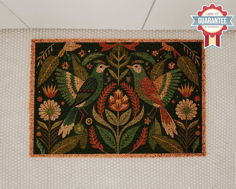 May include: A green and orange doormat with a floral and bird design. The doormat has a fringed border.
