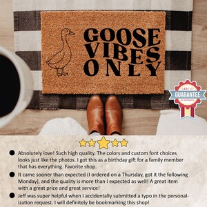 May include: A rectangular doormat with the text "GOOSE VIBES ONLY" in black. A line drawing of a goose is on the left. The mat is brown with a black and white striped border. Brown leather boots are in front of the mat.