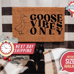 May include: A rectangular doormat with the text "GOOSE VIBES ONLY" and a goose illustration. The mat is brown with black text and a black goose outline. The background includes a black and white checkered pattern.