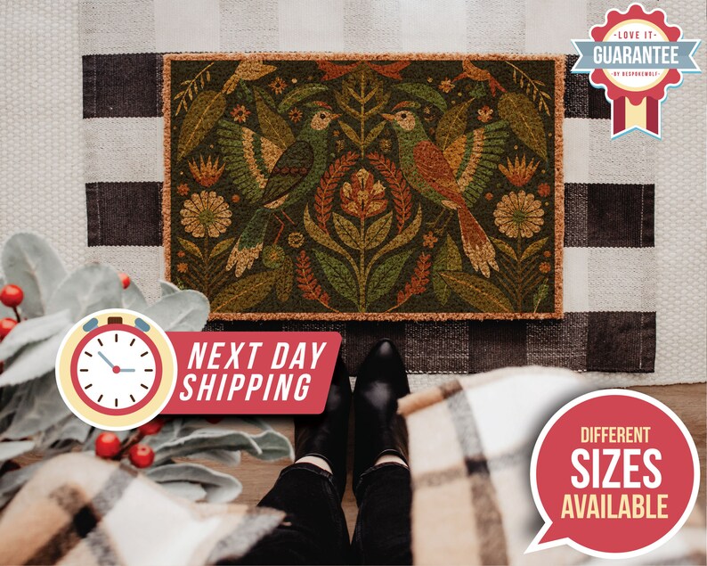 May include: A brown coir doormat with a colourful floral and bird design. The design features two birds with orange, brown, and green feathers, surrounded by green leaves and flowers with yellow, orange, and red accents.