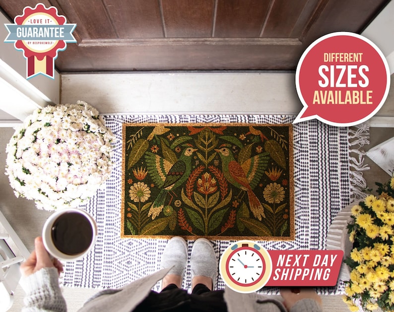 May include: A doormat featuring a colourful floral and bird design. The doormat is made of coir and has a natural brown colour. The doormat is placed on a white and blue patterned rug. The text "Different Sizes Available" is in a red speech bubble in the top right corner of the image. The text "Next Day Shipping" is in a red circle in the bottom right corner of the image.