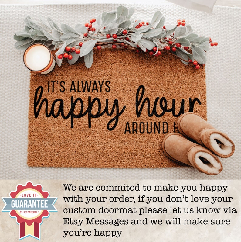 May include: A brown coir doormat with the text "IT'S ALWAYS happy hour AROUND HERE" in black lettering. The doormat is decorated with a sprig of greenery and red berries.
