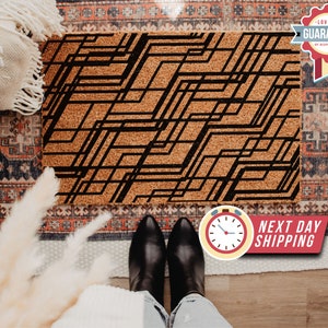 May include: A black and white geometric design printed on a cork doormat. The doormat is on a patterned rug.