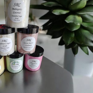 May include: Six jars of sugar scrub with different scents. The jars are labeled with the scent and the brand name "SRC".