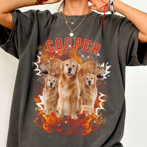 May include: Dark grey t-shirt with a graphic of five golden retrievers and the name "COOPER" in red. The design includes flames and lightning bolts. The shirt is oversized.