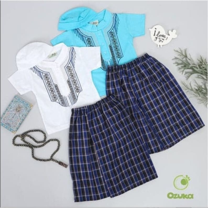 May include: Two sets of children's clothing for a special occasion. One set is white with blue embroidery and a white cap. The other set is light blue with blue embroidery and a light blue cap. Both sets include a pair of blue and black plaid pants.