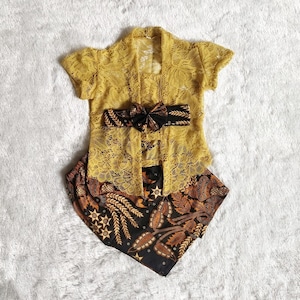 以下が含まれることがあります： 黄色のレースのトップスに、黒と茶色の模様の帯とそれに合わせたスカートを合わせたもの。トップスは半袖で、首回りは丸い形。スカートは花柄のミニスカートです。