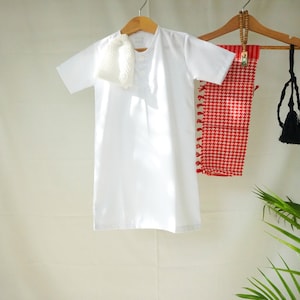 May include: White short-sleeved shirt with a white scarf, red and white checkered fabric, and a black tassel hanging from a wooden hanger.