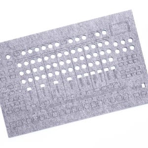 May include: A gray felt panel with cut-out shapes resembling a sound mixing board. The panel has numerous circular and rectangular openings, along with slider-like cutouts. A small potted plant is in the upper right corner. The text "WaveTable 2025" is in the lower right corner.