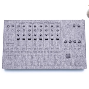 Peut inclure: Un tapis en feutre gris avec un motif imprimé d'une console de production musicale. Le tapis a une grille de boutons, de boutons et de curseurs.