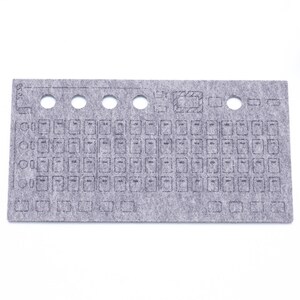 May include: A gray felt mat with a grid of 60 squares and 5 rows of holes. The mat is designed to hold small objects, such as beads or buttons.